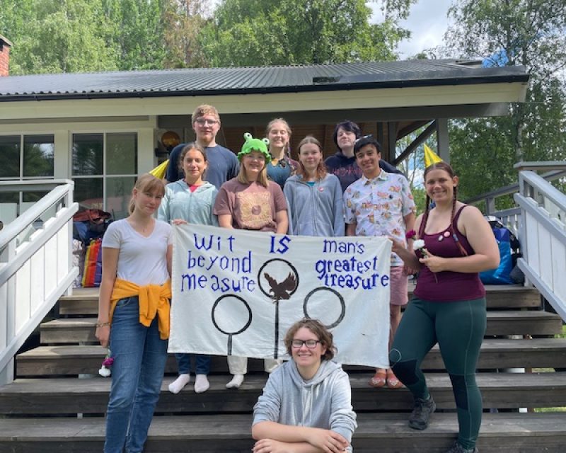 en samling medlemmar lyfter en banner inspirerad av Harry Pottervärlden